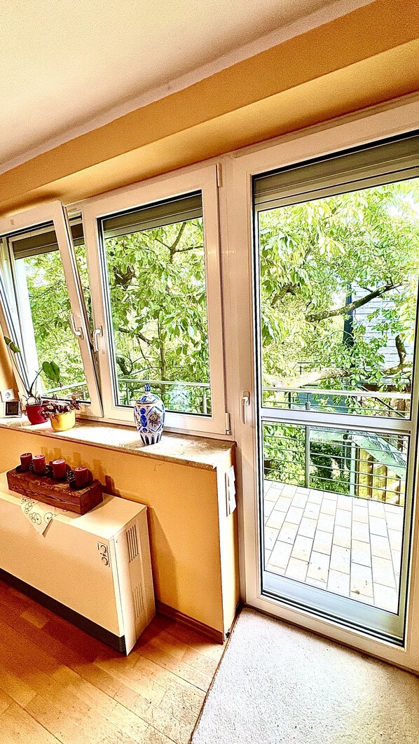 Una habitación con radiador, ventana con vistas a zonas verdes y una mesa con un pastel.