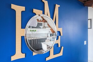 Una cocina moderna con un espejo grande, letras de madera en la pared y una pared azul.