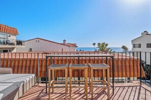 Une terrasse sur le toit, avec une table et des chaises en bois, un canapé et une vue sur la mer.