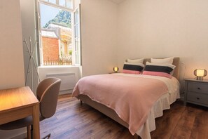 Ein Schlafzimmer mit einem Bett, Nachttischen, einem Schreibtisch und einem Sessel.