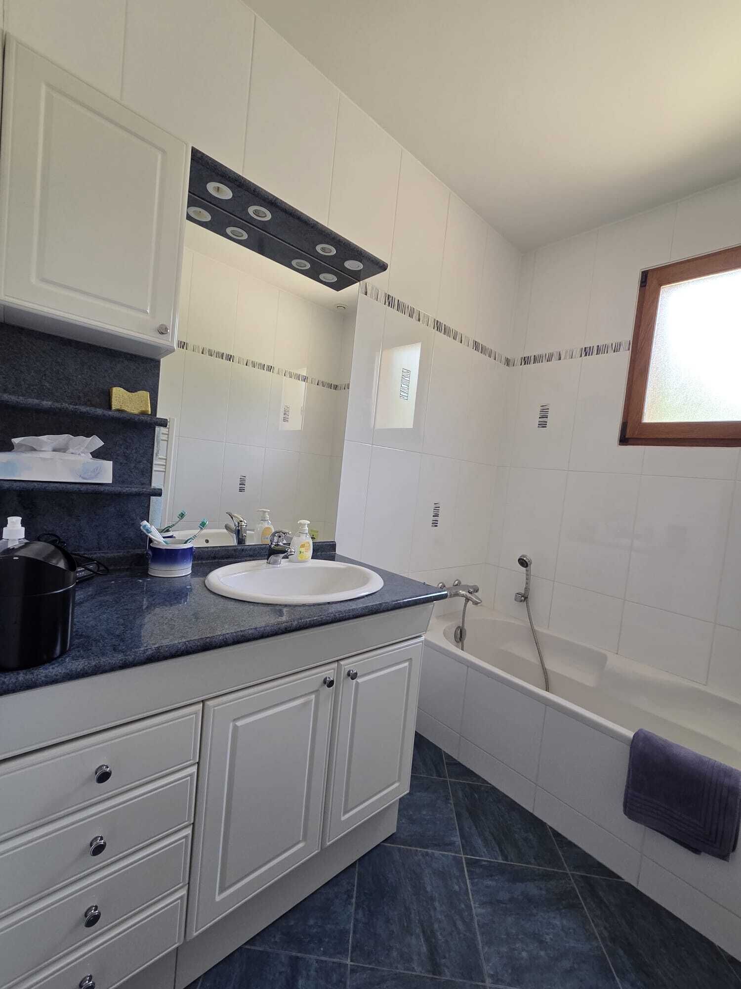 Een badkamer met een wit wastafel, een bad en een raam.