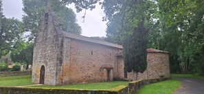 A stone building with a tiled roof, arched door, and windows, surrounded by greenery. - Large and peacefull house with a panoramic view of Belvès, in Black Perigord (Pays de Belvès)