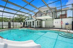 Ein Schwimmbad mit Rutsche, überdachtem Bereich und einem Haus im Hintergrund.