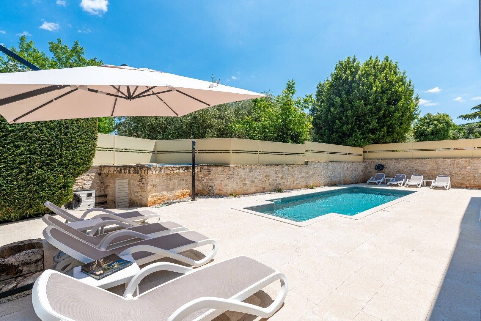 A swimming pool with lounge chairs and an umbrella.