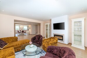 Ein Wohnzimmer mit Fernseher, Kamin und Glastisch.