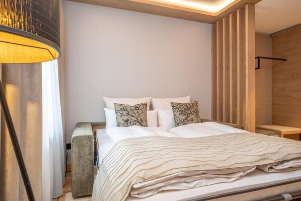 A modern bedroom with a bed, pillows, a bedside table, and a lamp. - Gasthof zur Post (Bad Wiessee)