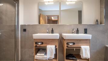 Un baño moderno con dos lavamanos, armarios de madera y un espejo grande.