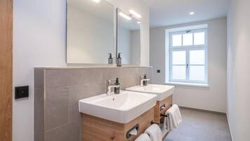Un baño moderno con dos lavamanos, un espejo grande y una ventana.