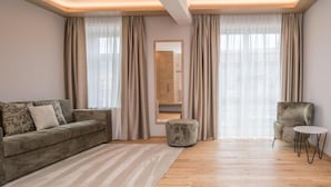 Una sala de estar moderna con sofá, reposapiés, sillón y una mesa redonda.