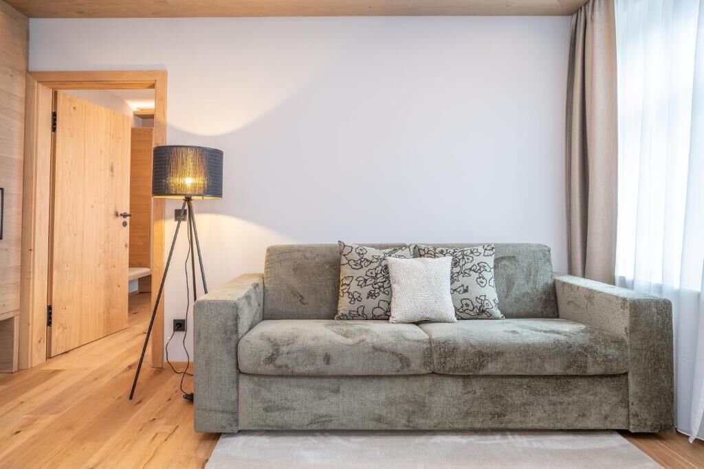Una sala de estar con un sofá, una lámpara y una puerta que da a otra habitación.