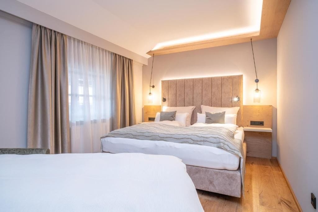 A modern hotel room with a large bed, bedside tables, and a headboard with integrated lighting.