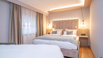 A modern hotel room with a large bed, bedside tables, and a headboard with integrated lighting.