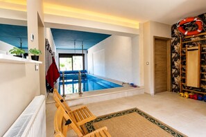 Ein Pool mit Blick ins Freie, ein Holzstuhl und ein Rettungsring an der Wand.