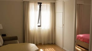 Et hotelværelse med en seng, en stol, et skrivebord og et klædeskab.