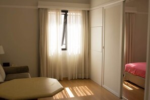 A hotel room with a bed, a chair, a desk, and a wardrobe. - Apartment in Jardins with parking space and pool. (São Paulo)