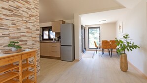 Eine moderne Küche mit Kühlschrank, Schränken und einer Essecke mit Stühlen und Tisch.