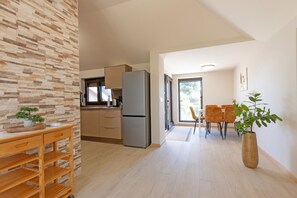 Eine moderne Küche mit Kühlschrank, Schränken und einer Essecke mit Stühlen und Tisch.