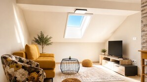 Ein modernes Wohnzimmer mit einer Couch, einem Couchtisch, einem Fernseher und einer kleinen Pflanze.