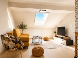 Ein modernes Wohnzimmer mit einer Couch, einem Couchtisch, einem Fernseher und einer kleinen Pflanze.