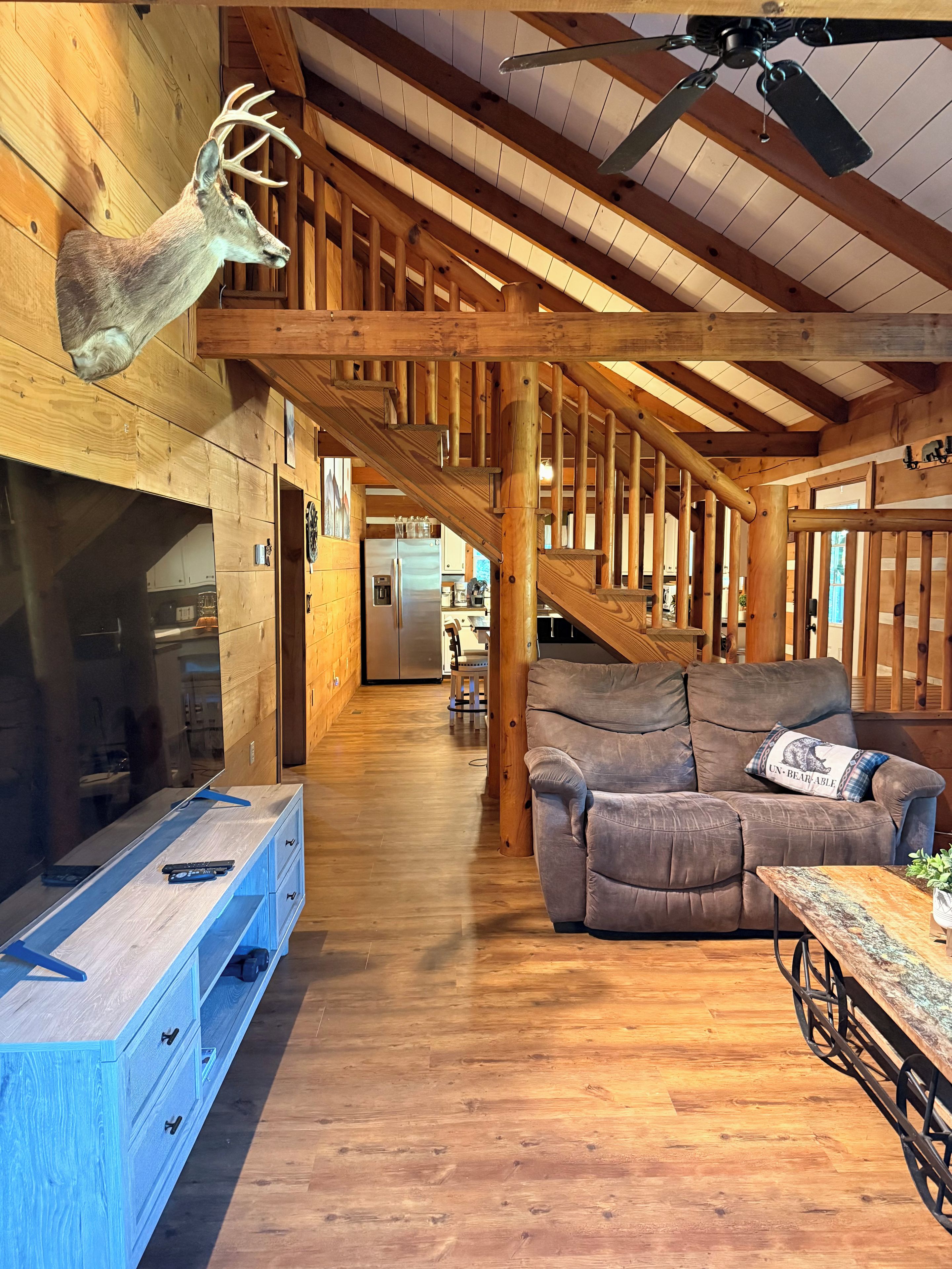 Een houten interieur met een open haard, een bank en een plafondventilator.