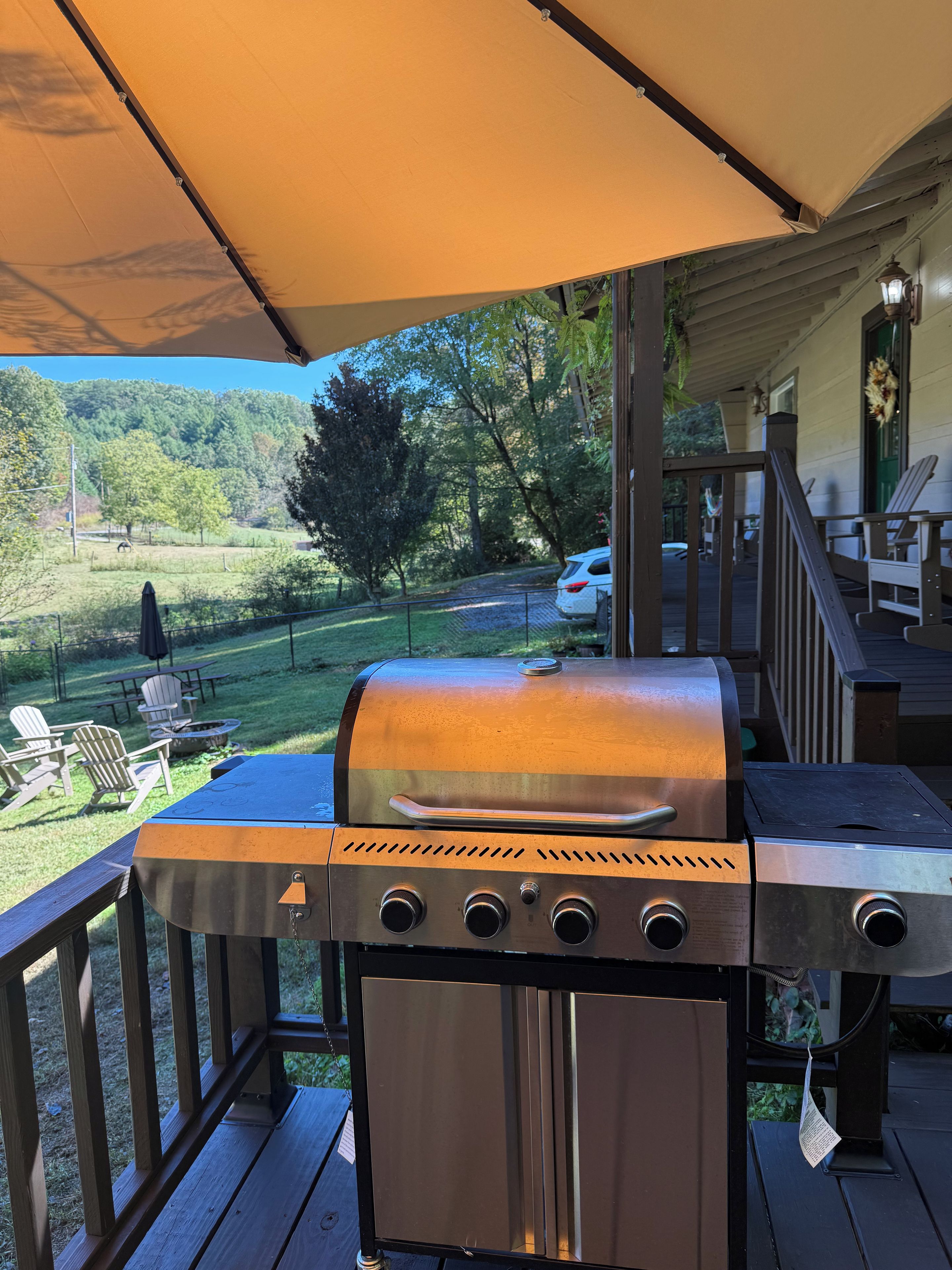 A barbecue grill on an outdoor deck with a view of a wooded area.