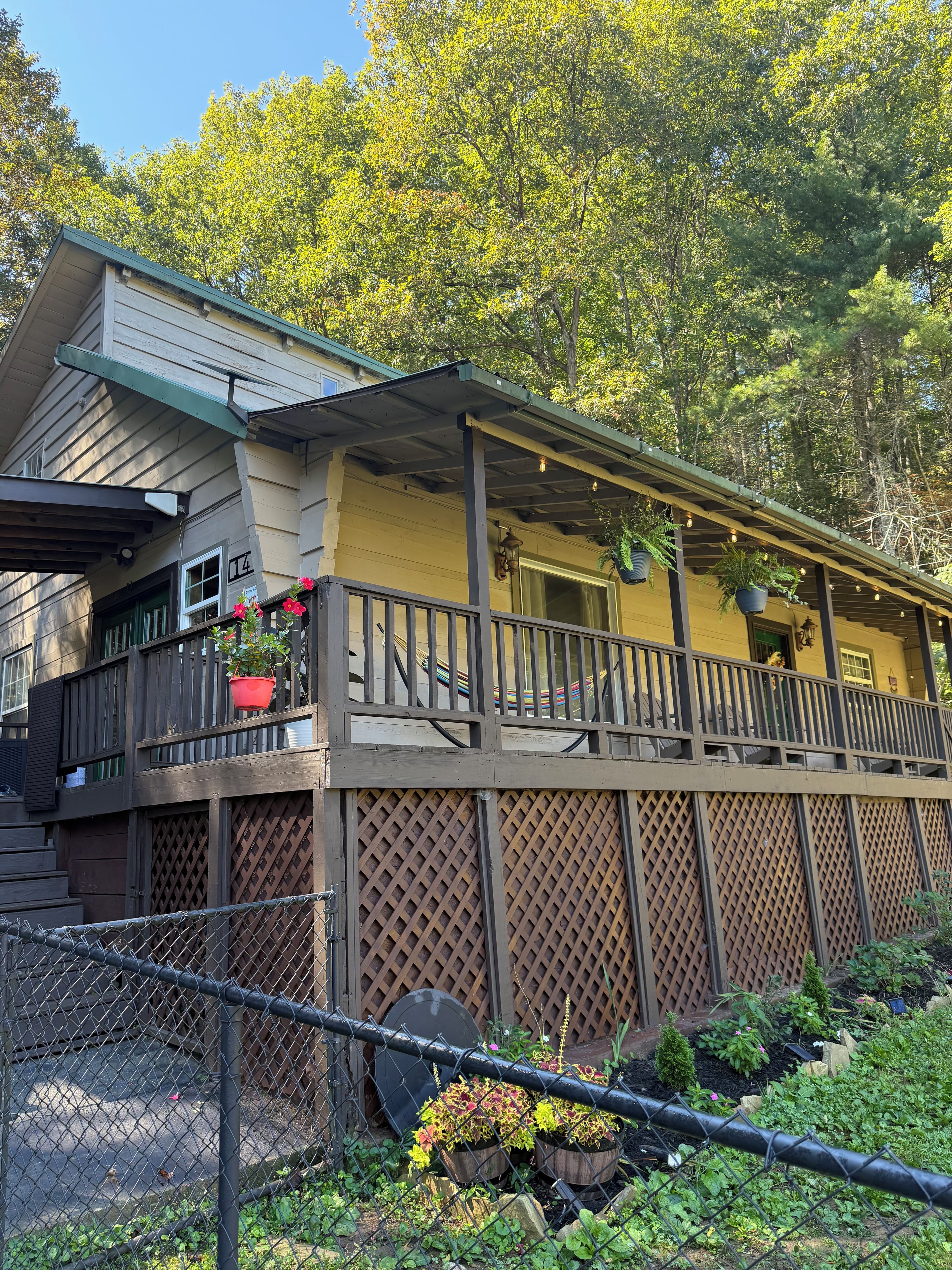A two-story building with a balcony, a wooden fence, and a garden area.