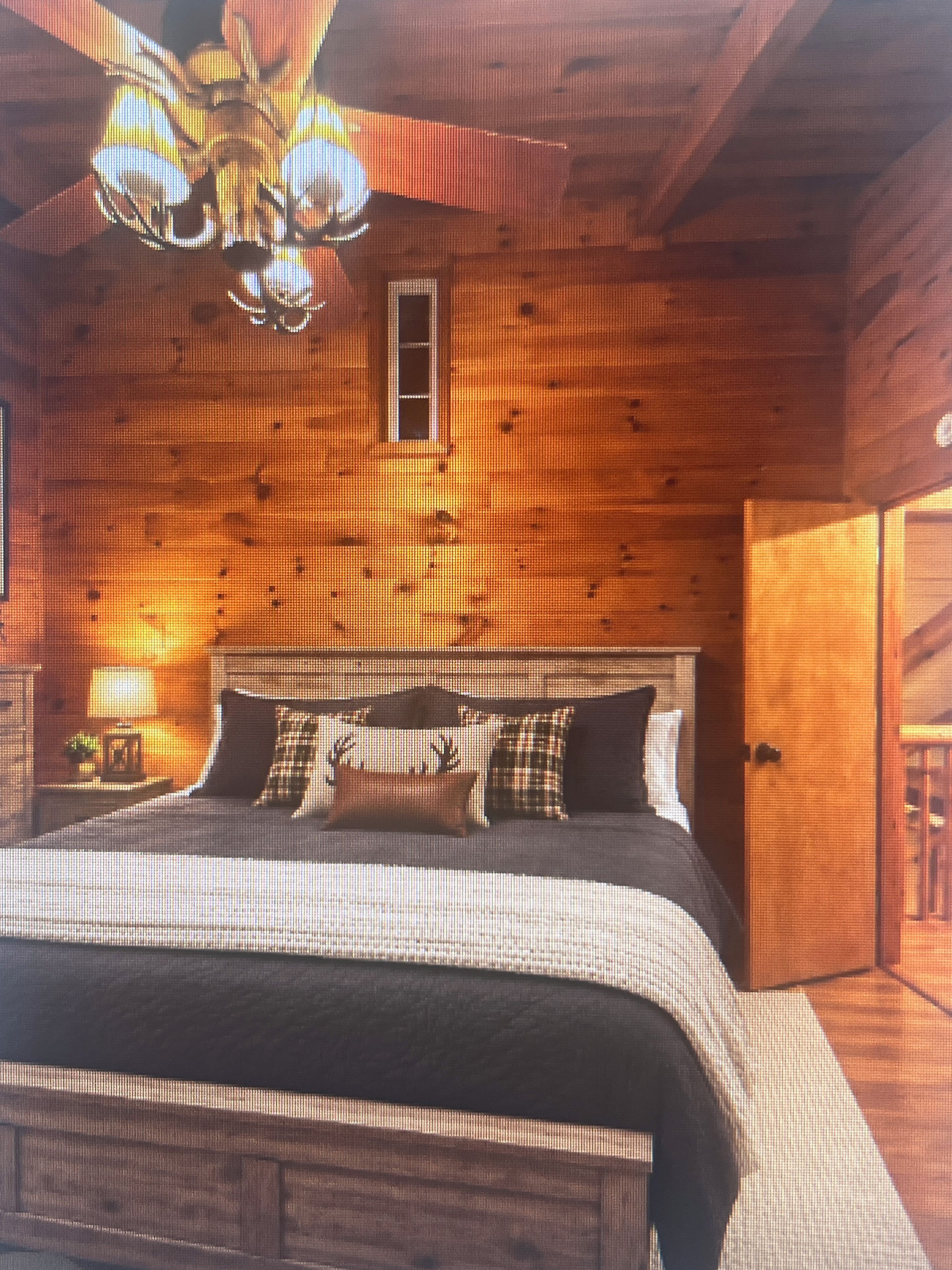 A wooden cabin interior with a bed, a window, and a door.