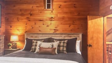 A wooden cabin interior with a bed, a window, and a door.