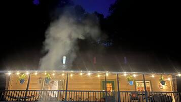 A building with a porch, outdoor seating, and a smoke effect.
