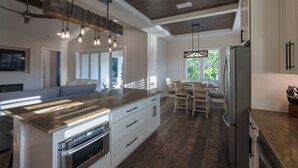 Une cuisine moderne dotée d’un îlot central, d’appareils électroménagers en acier inoxydable et d’un coin repas avec des chaises en bois.