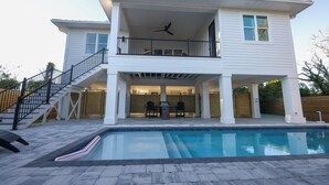 Une maison à deux étages avec un balcon, une piscine et un escalier.