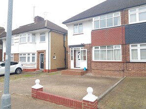 A residential area with houses, a paved driveway, and a parked car. - Stylish, Spacious  4‑Bedroom House Near London • Ideal for Groups & Contractors (Potters Bar)
