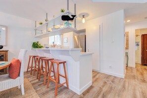 Eine Küche mit einer weißen Kochinsel, Barhocker und einer Leuchte in Katzenform.