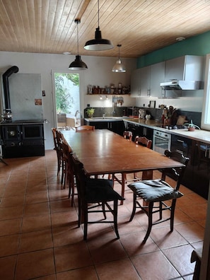 Une cuisine avec une table et des chaises en bois, un fourneau et des placards.