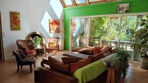 A cozy living room with a fireplace, comfortable seating, and a large sliding glass door leading to a balcony. - Large, single-story, air-conditioned house with 5 bedrooms near the Marais Poitevin (Saint-Pierre-d'Amilly)