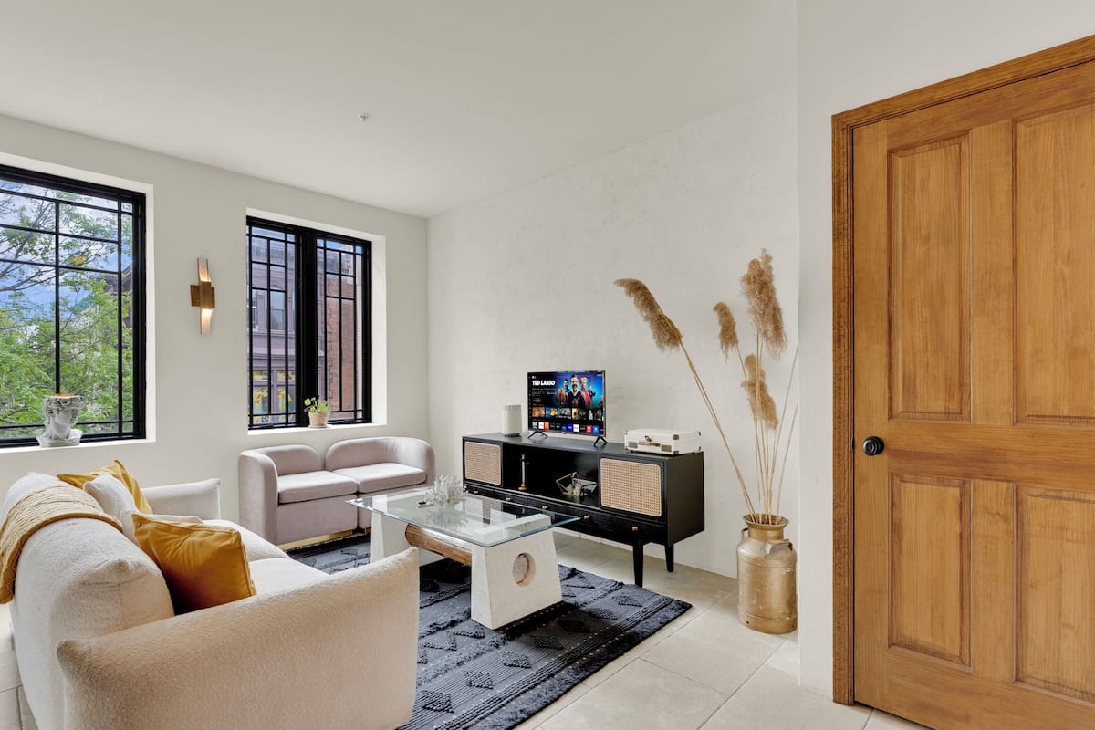 A living room with a sofa, coffee table, TV, and decorative plants.