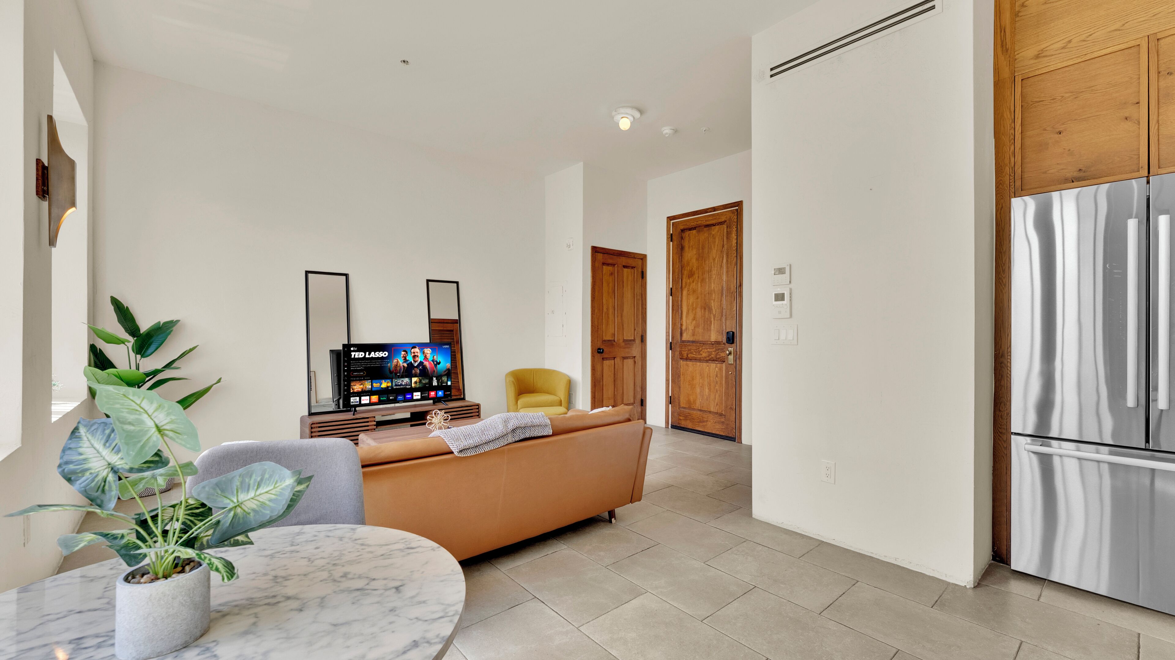 A modern living room with a sofa, TV, and a potted plant.