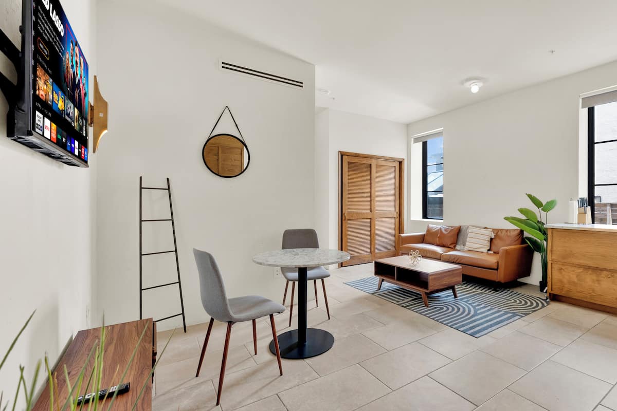 A modern living room with a sofa, coffee table, and a dining area with chairs.