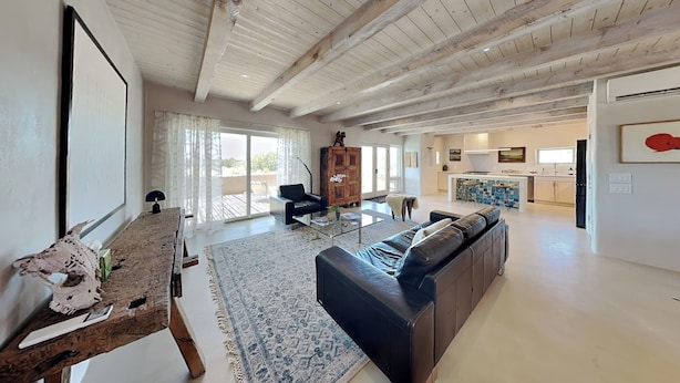 A spacious living area with a wooden ceiling, a sofa, a coffee table, and a view of the outside.