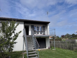 A two-story building with a balcony, a staircase, and a satellite dish. - Villa Jo - Family Home in Grand-Village (Le Grand-Village-Plage)