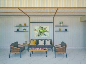 Een moderne woonkamer met een bank, twee fauteuils, een salontafel en een groot abstract schilderij aan de muur.
