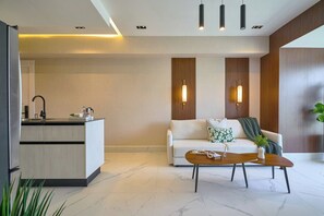 Un espace de vie moderne comprenant un canapé, une table basse et un coin cuisine avec un évier et un plan de travail.