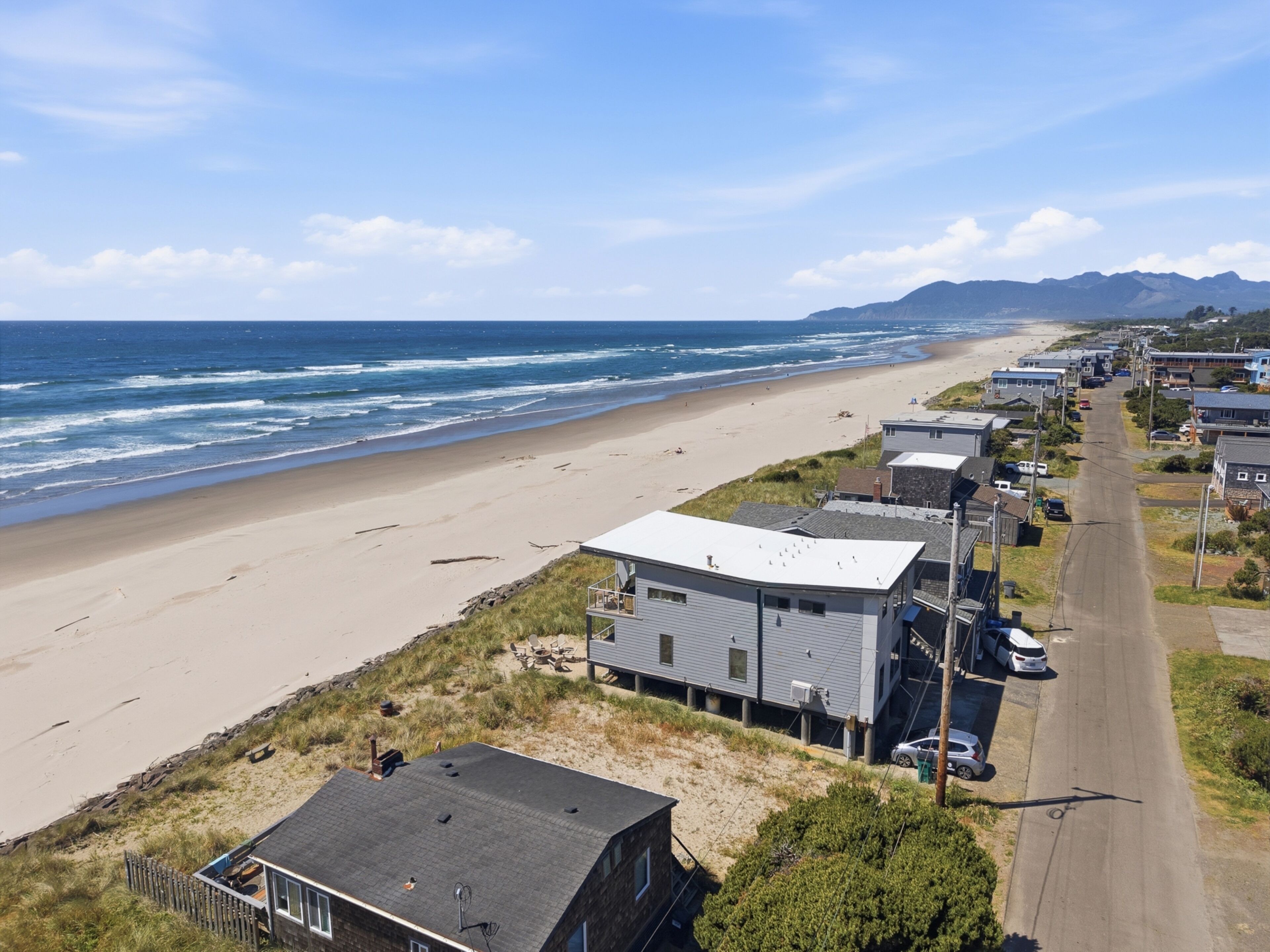 A coastal residential area with houses, a beach, and a road.