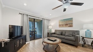 A modern living room with a flat-screen TV, a sofa, a coffee table, and a ceiling fan. - 🏖️Steps to Beach | Covered Patio | Seaside Beach and Raquet 2101🌴 (Orange Beach)