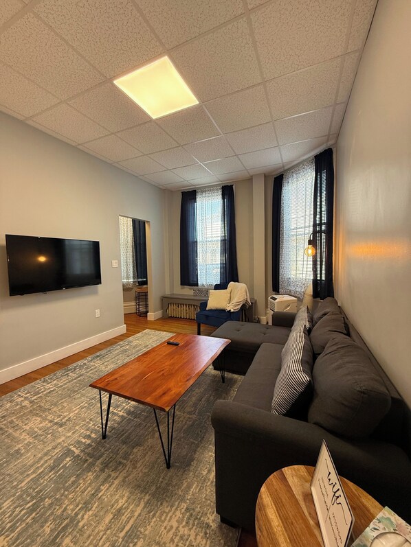 Una sala de estar moderna con un televisor de pantalla plana, un sofá, una mesa de centro y una alfombra estampada.