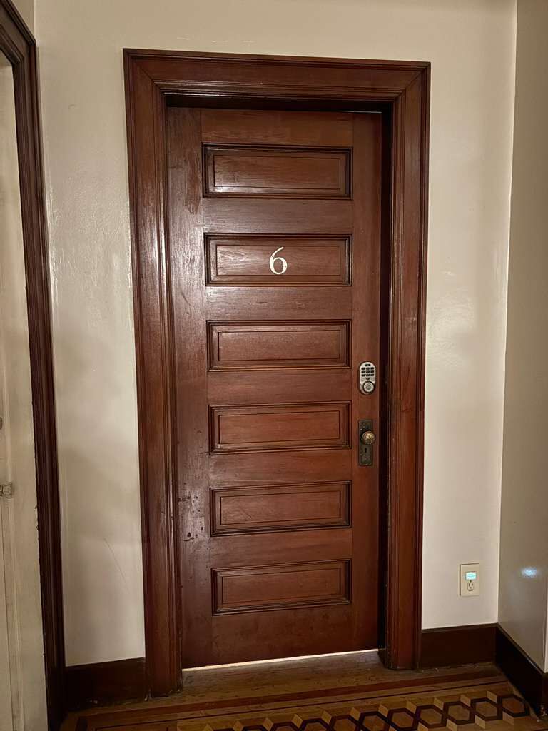 A wooden door with a number '6' and a keypad lock.