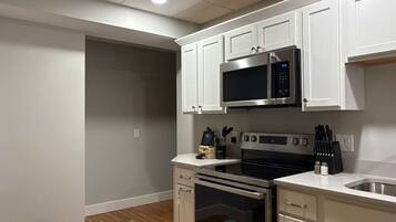 A modern kitchen with white cabinetry, a stainless steel microwave, a built-in oven, and a sink.