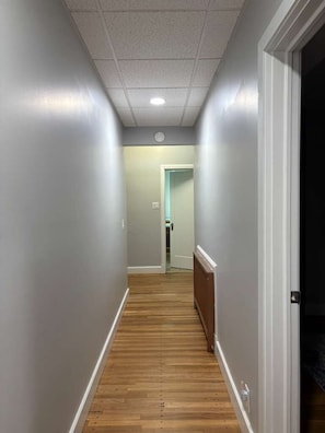 A narrow hallway with wooden flooring and light gray walls. - NH6 - Modern 2BR Retreat in a Historic House (DuBois)