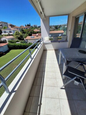 A balcony with a view of houses, a tiled floor, and a chair. - Air-conditioned 2-room apartment with a terrace, a 3-minute walk from the beach and restaurants (Cagnes-sur-Mer)
