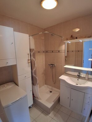 A bathroom with a shower, a sink, and a mirror. - Air-conditioned 2-room apartment with a terrace, a 3-minute walk from the beach and restaurants (Cagnes-sur-Mer)